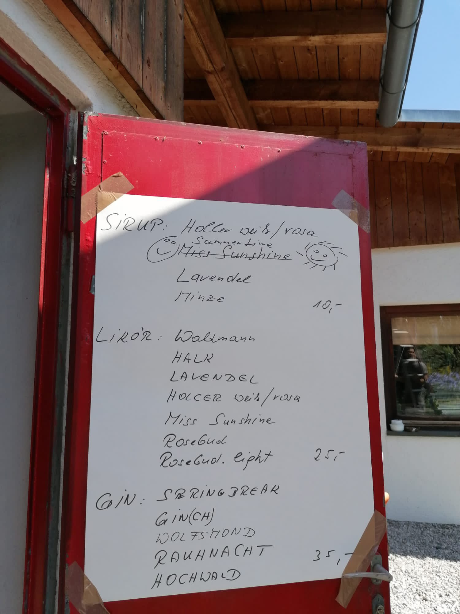 Kleines Menü Auf einer roten Metalltür wurde eine handgeschriebene Getränkekarte aufgeklebt